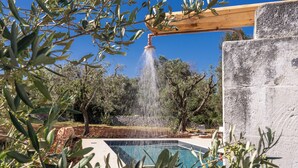A pool with a water feature, surrounded by olive trees and a stone wall. - Trullo Orto dei Nonni - Le Case di Valentina (Ceglie Messapica)
