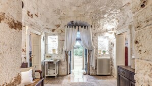 A rustic stone-walled room with a wooden bench, a small table with a bowl, and a radiator. - Trullo Orto dei Nonni - Le Case di Valentina (Ceglie Messapica)