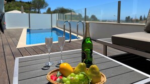 A poolside table with a bottle of champagne, two glasses, and a basket of fruit. - ALBUFEIRA DELUXE RESIDENCE WITH POOL by HOMING (Albufeira)