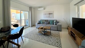 A modern living room with a grey sofa, a coffee table, and a TV stand. - ALBUFEIRA DELUXE RESIDENCE WITH POOL by HOMING (Albufeira)