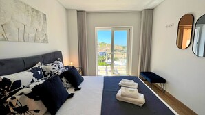 A modern hotel room with a bed, a sofa, a large window, and a view of the outdoors. - ALBUFEIRA DELUXE RESIDENCE WITH POOL by HOMING (Albufeira)