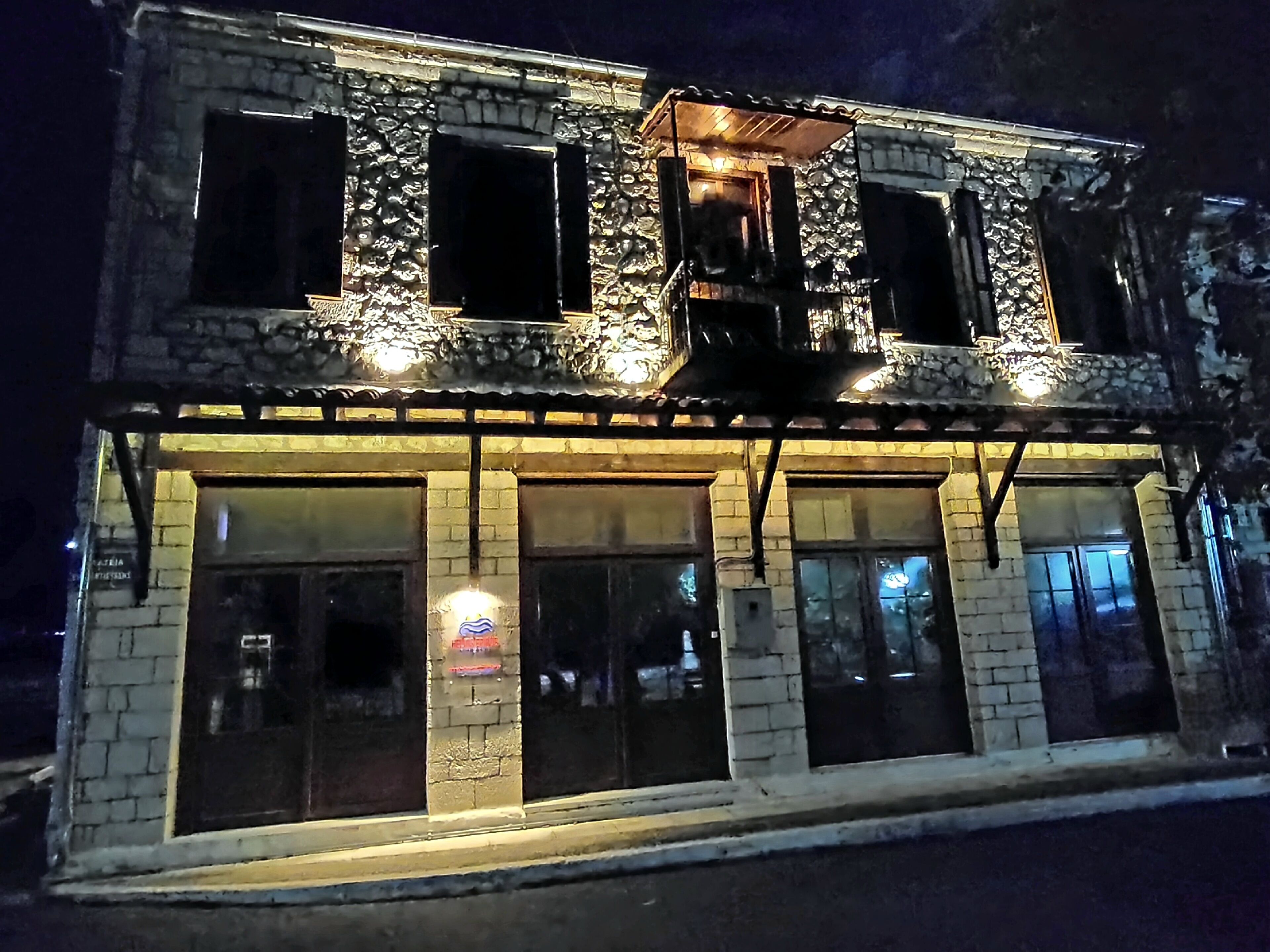 Um edifício de dois andares com varanda e grandes janelas.