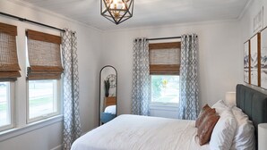 A bedroom with a bed, curtains, a mirror, and artwork on the wall. - Hopp's Downtown Loft (McPherson)