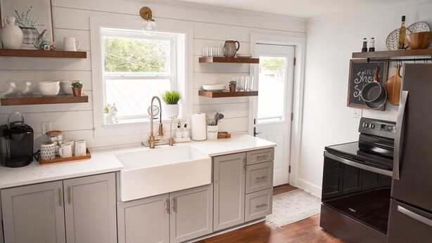 A kitchen with white cabinetry, a black stove, and wooden shelves. - Hopp's Downtown Loft (McPherson)