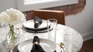 A dining table set with white plates, black napkins, and a vase of white flowers. - Hopp's Downtown Loft (McPherson)