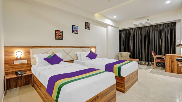 Quarto de hotel com duas camas, uma escrivaninha, uma cadeira e um ar condicionado.