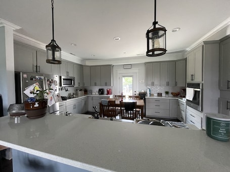 A modern kitchen with grey cabinets, a central island, and pendant lighting.