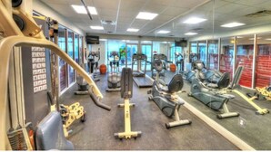 Et fitnesscenter med forskellig træningsudstyr, herunder løbebånd, motionscykler og styrkemaskiner.
