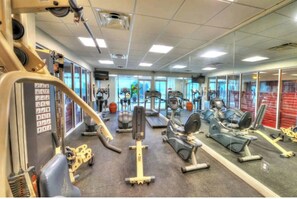 Ein Fitnessstudio mit verschiedenen Trainingsgeräten, darunter Laufbänder, Ergometer und Kraftgeräte.