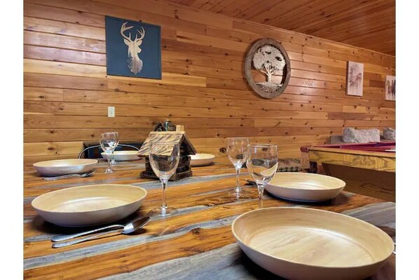 Enjoy a formal dining experience in this cozy cabin, complete with a beautifully set table and rustic charm.