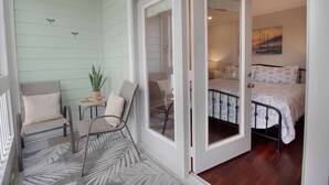 A room with a bed, two chairs, a small table with a plant, and a window. - Lovely Long Term Rental~ Marsh Nest (Folly Beach)
