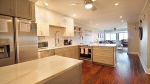 A modern kitchen with stainless steel appliances, wooden flooring, and a ceiling fan. - Lovely Long Term Rental~ Marsh Nest (Folly Beach)