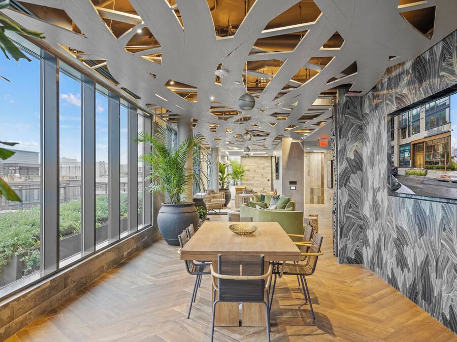 A spacious indoor area with a large wooden table, chairs, and potted plants.