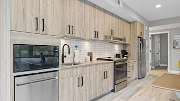 Una cocina moderna con armarios de madera, electrodomésticos de acero inoxidable y un ventanal amplio.