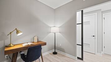 A study area with a desk, two lamps, a chair, and a door.