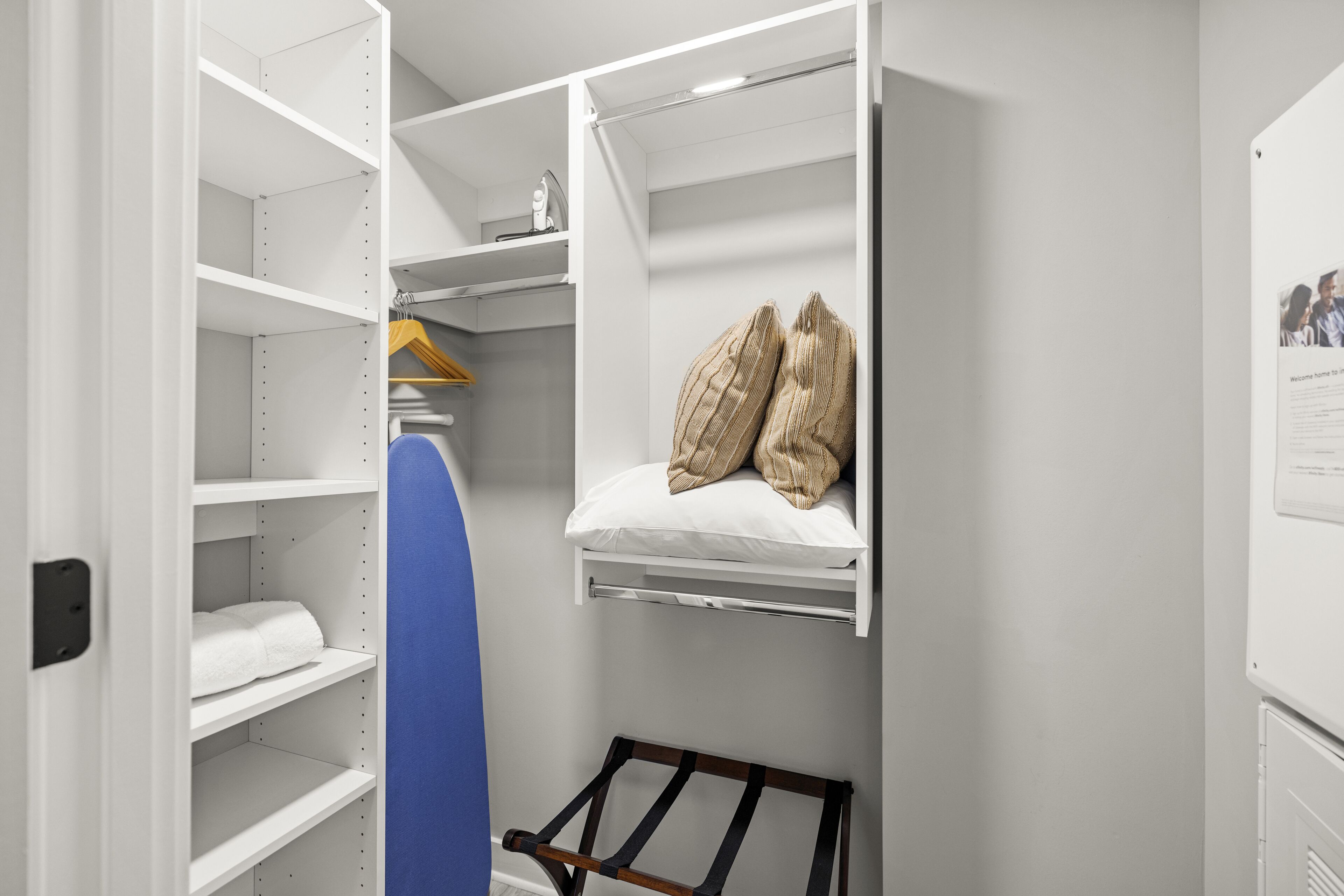 Un vestidor amplio con estantes abiertos, una barra para colgar ropa y una cama con almohadas.