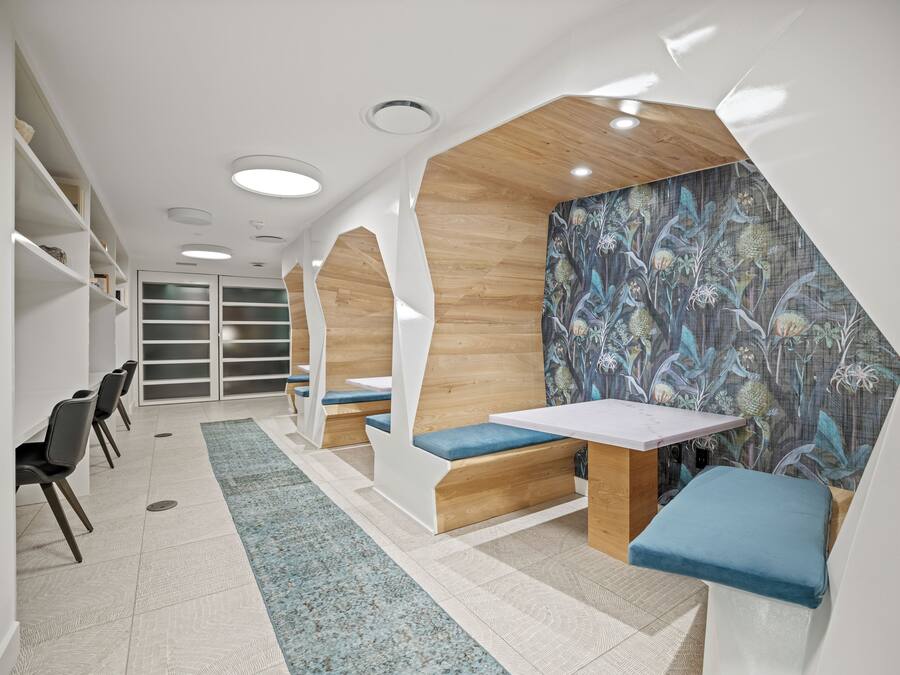 Um interior moderno com áreas de estar, uma mesa e uma parede estampada.