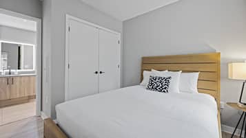 Een moderne slaapkamer met een groot bed, een houten hoofdbord en een nachtkastje.