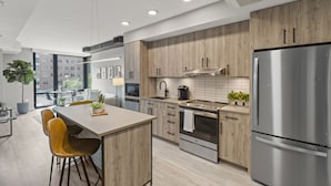 Una cocina moderna con armarios de madera, electrodomésticos de acero inoxidable y una isla central con taburetes de bar.
