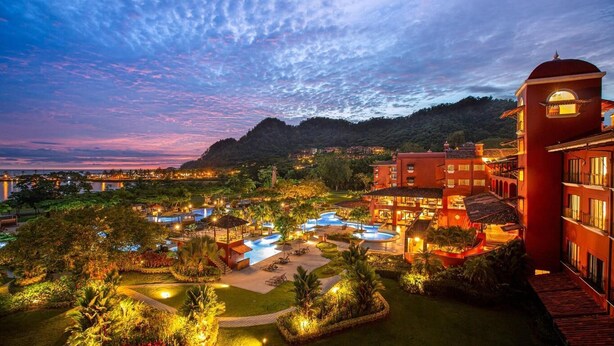 A resort with multiple swimming pools, a large building with a dome, and lush greenery.
