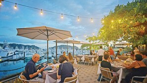 An outdoor dining area with tables and chairs, umbrellas, and string lights.