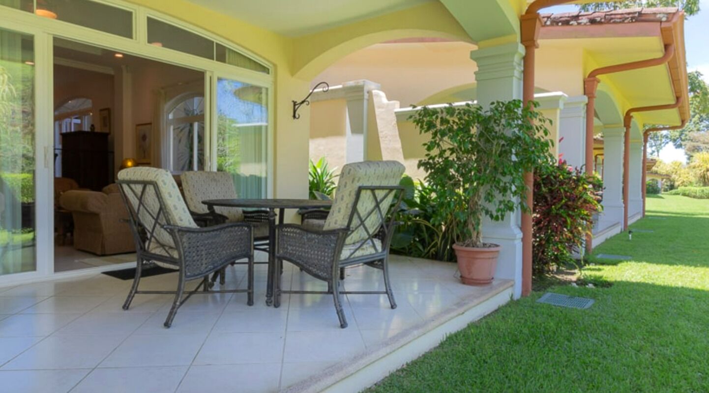 A patio with wicker furniture and a potted plant.