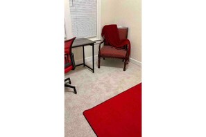 Cozy retreat with a single chair, table, and plush carpet.