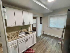 Compact kitchen with a stainless steel sink, granite countertop, and a refrigerator.