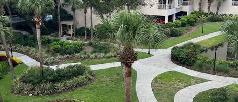 A modern hotel with a landscaped garden, a winding pathway, and a multi-story building with balconies.