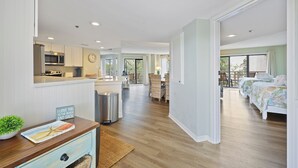 A spacious room with a large bed, a desk with a plant, and a view of the outdoors. - BEAUTIFULLY RENOVATED, OCEAN VIEW - VILLAMARE. PICKLEBALL-TENNIS INCLUDED.   (Hilton Head Island)