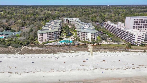 A resort with multiple buildings, a central pool, and a beach in the foreground. - BEAUTIFULLY RENOVATED, OCEAN VIEW - VILLAMARE. PICKLEBALL-TENNIS INCLUDED.   (Hilton Head Island)