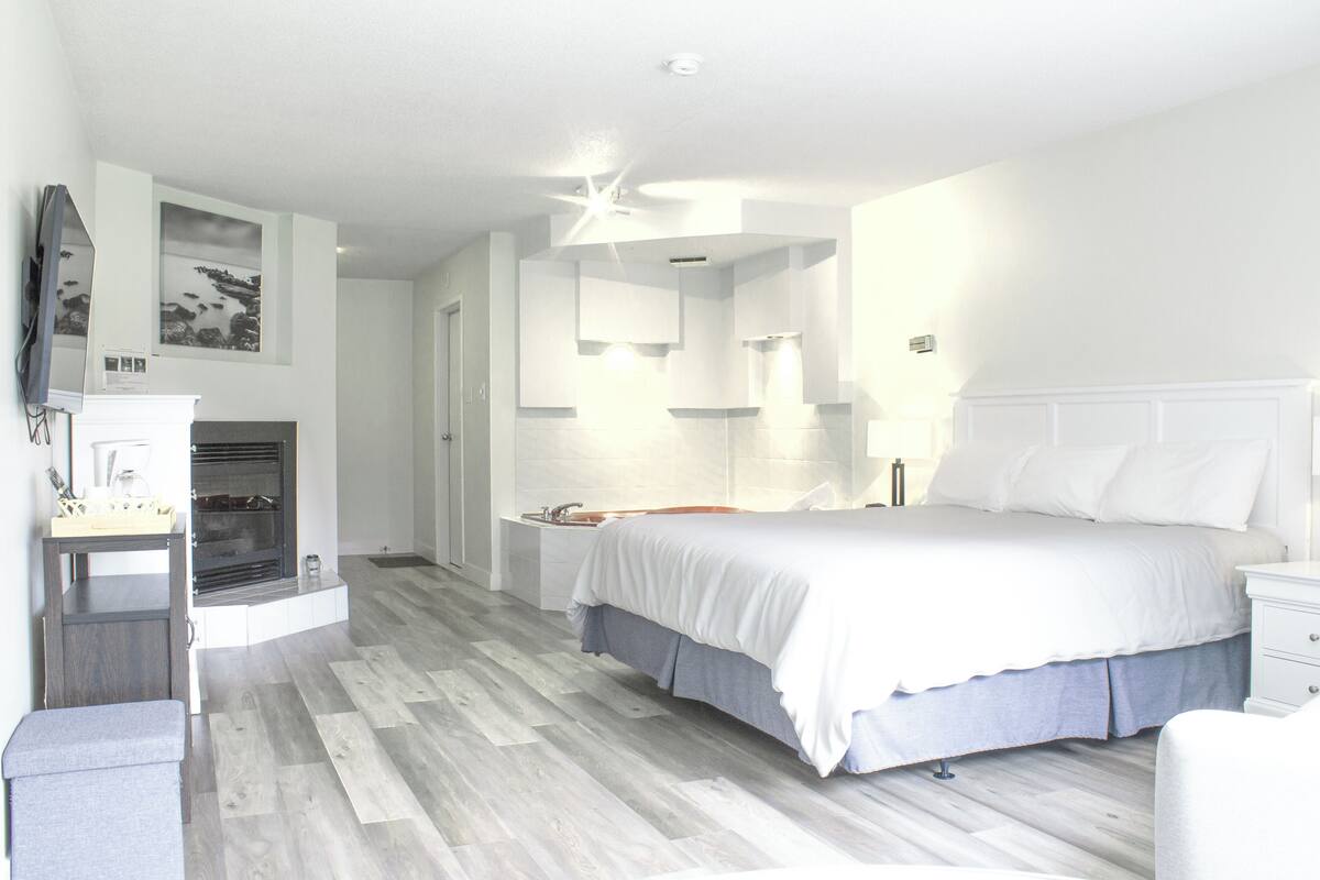 Een moderne slaapkamer met een groot bed, een bureau en een in de muur gebouwde open haard.