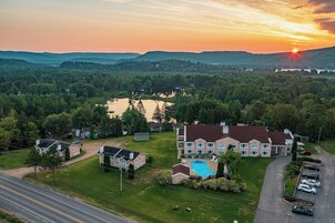 Una casa grande con piscina, rodeada de un paisaje exuberante y un lago.