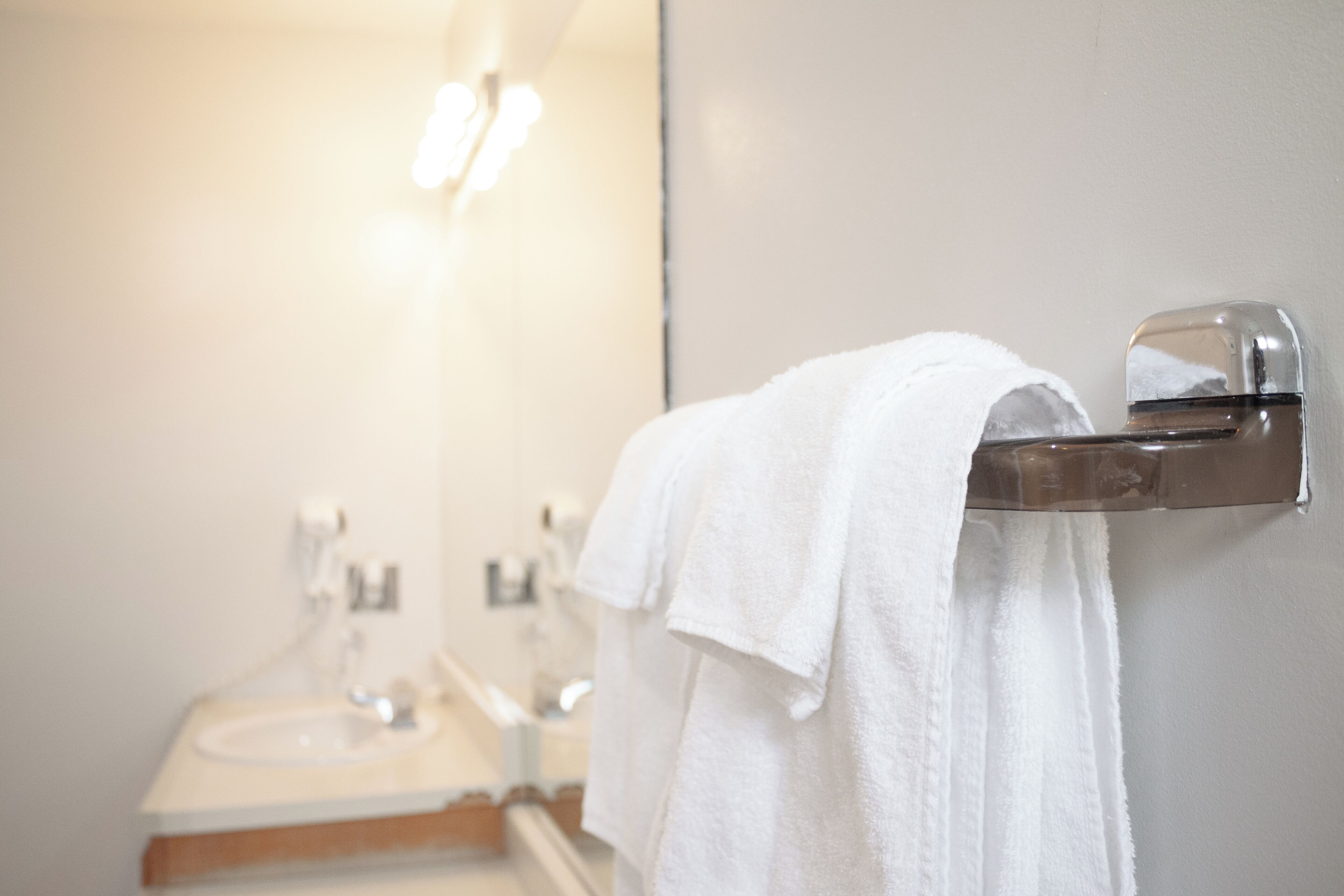 A bathroom with a sink, mirror, and towel rack.