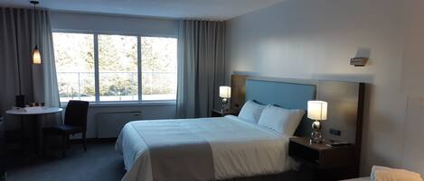 A hotel room with a large bed, bedside lamps, a desk, and a chair.