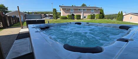 A hot tub in a backyard with a house in the background.