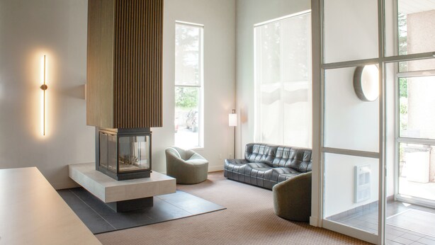 A modern living room with a fireplace, a sofa, and a coffee table. - Hôtel Matha (Saint-Jean-de-Matha)