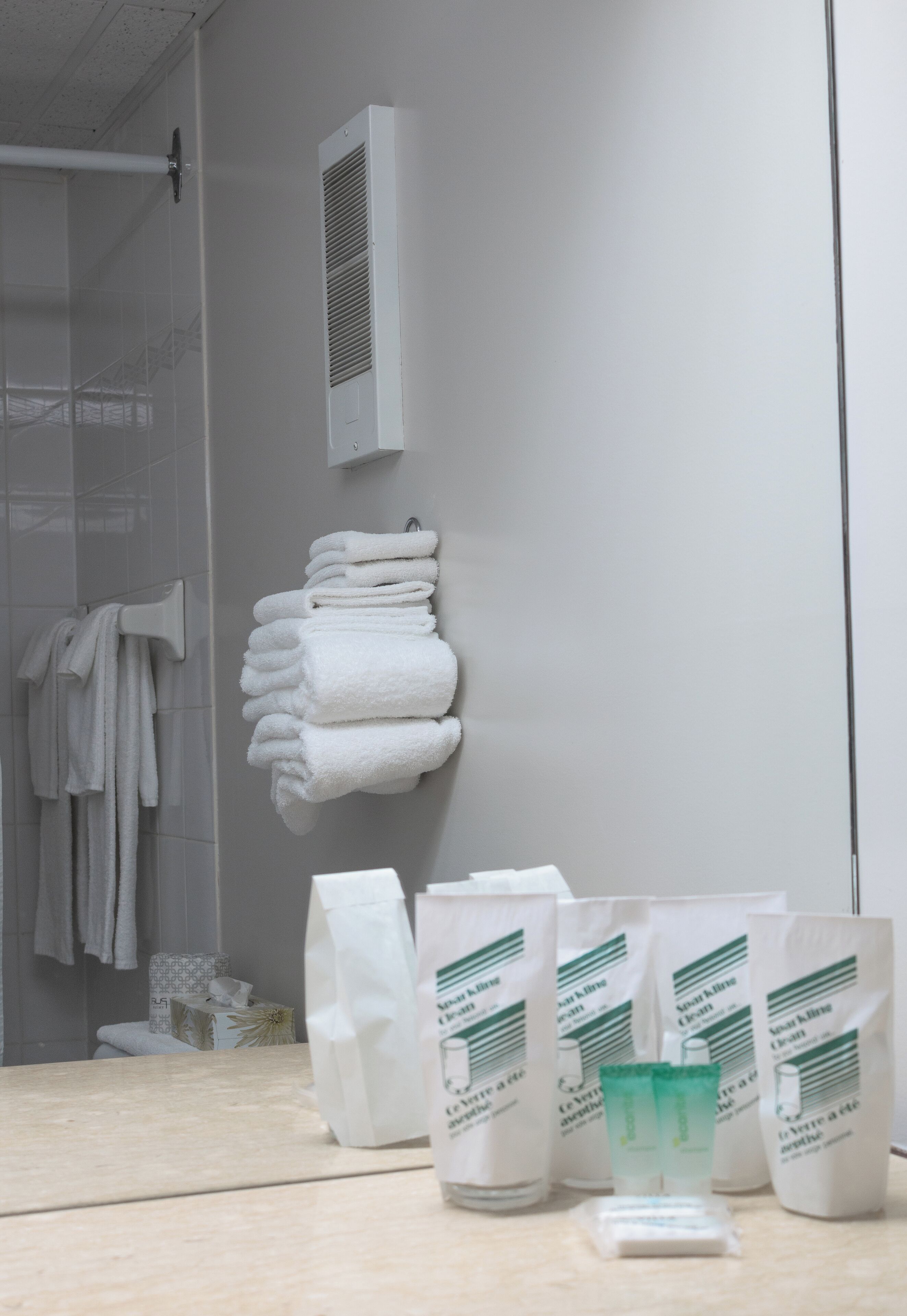 A bathroom with a towel rack, a shower area, and toiletries on the counter.