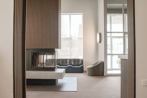 Una sala de estar moderna con chimenea, un sofá y un ventanal grande.