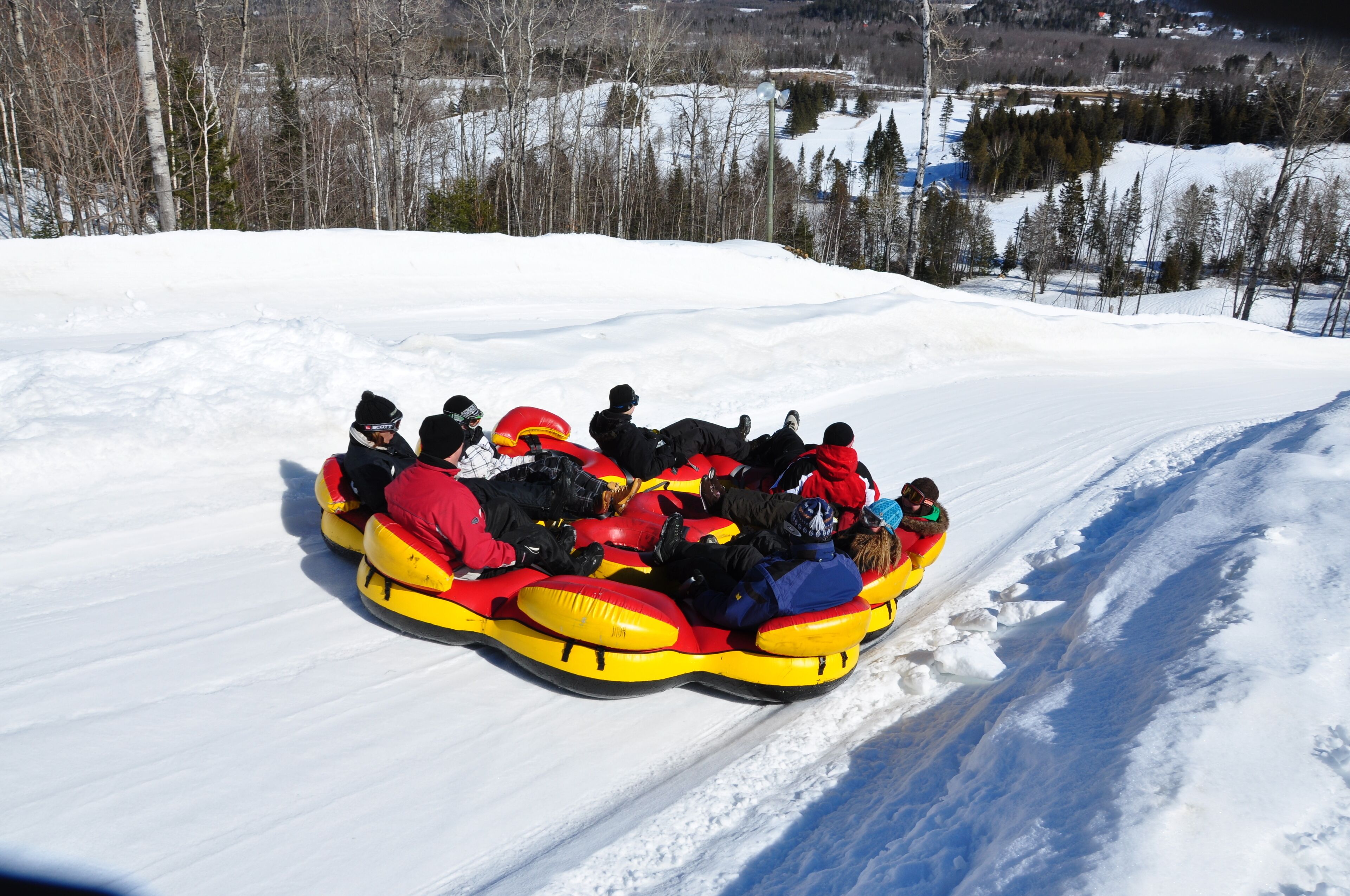 A group of people in a yellow snow tube on a snowy slope.