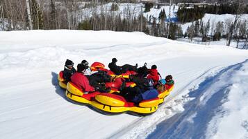A group of people in a yellow snow tube on a snowy slope.