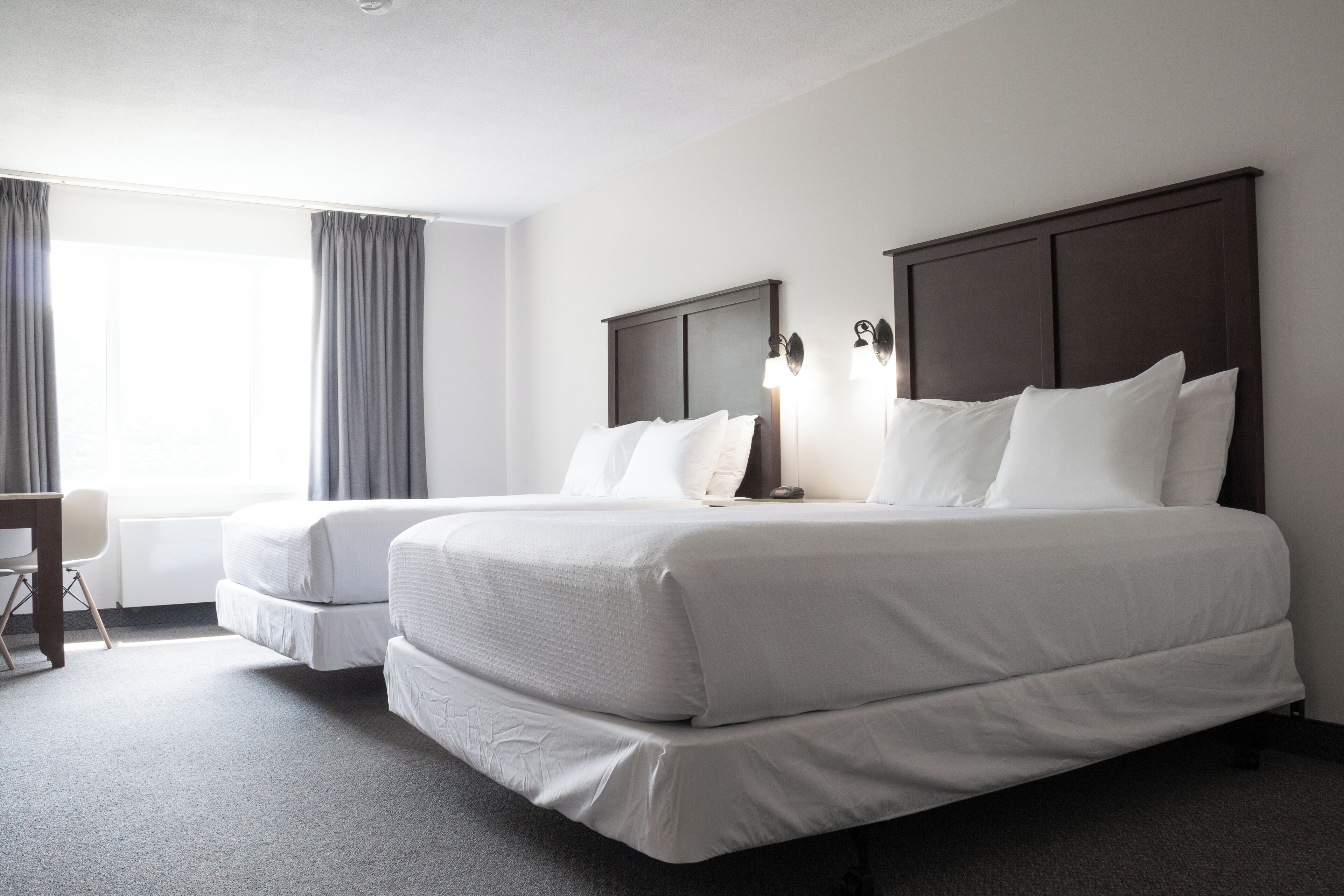 Een hotelkamer met twee bedden, een bureau en een stoel.