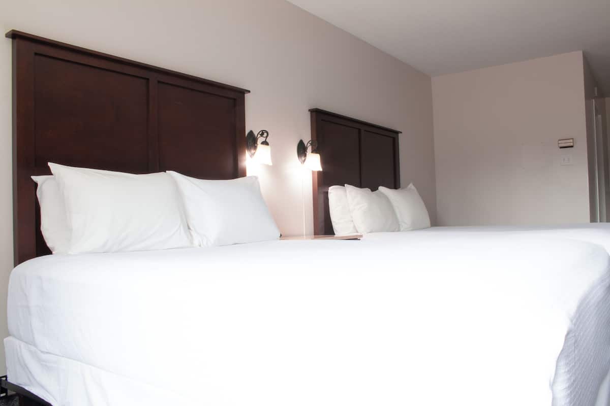 Een hotelkamer met een groot bed, een houten hoofdbord en twee bedlampen.