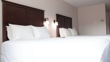 Una camera d'albergo con un letto grande, una testiera in legno e due abat-jour.
