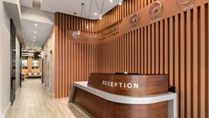 Un espace d’accueil avec un comptoir en bois portant l’inscription « RÉCEPTION » et un mur recouvert de lambris en bois verticaux.