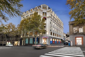 A multi-story hotel with a classic architectural style, featuring a prominent entrance and a large tree in front. - Tbilisi Chambers, Trademark Collection by Wyndham (Tbilisi)