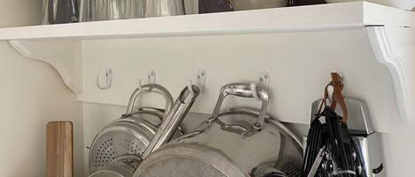 A kitchen with stainless steel cookware, glassware, and a potted plant.