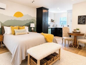 Une chambre à coucher comprenant un lit, une table de chevet, un banc et un mur décoré d’un motif de montagne.