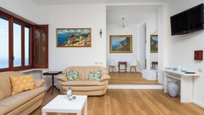 A living room with a beige sofa, a white coffee table, and two paintings on the wall. - Villa Cristina (Piano di Sorrento)