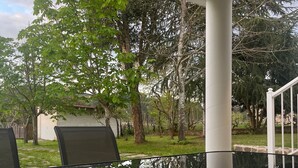 Une table en verre qui reflète les arbres et une rambarde blanche.